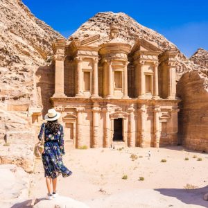 Asian young woman in colorful dress and hat enjoying at The Monastery, Petra's largest monument, UNESCO World Heritage Site, Jordan.