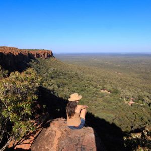 Girl sitting on stone on the cliff at an african landscape. Waterberg plateau, Namibia. Relax time on holiday concept travel.